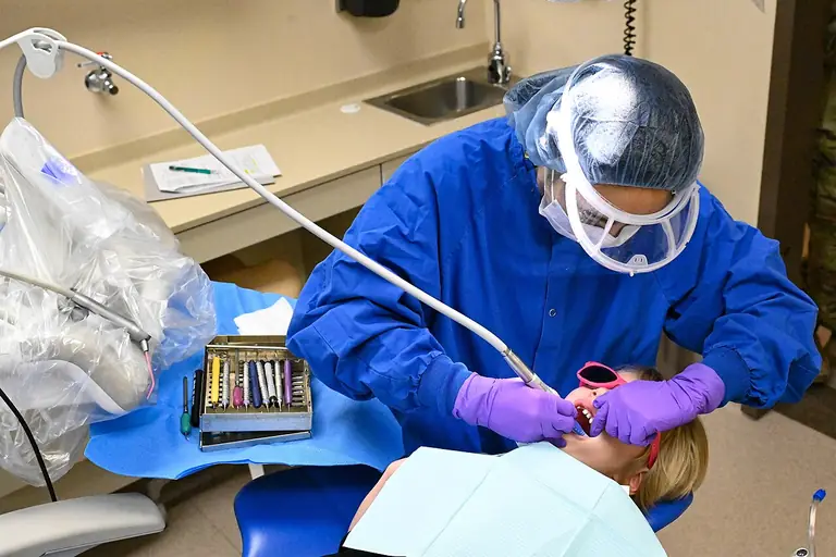 Dentist in a face shield treating a patient